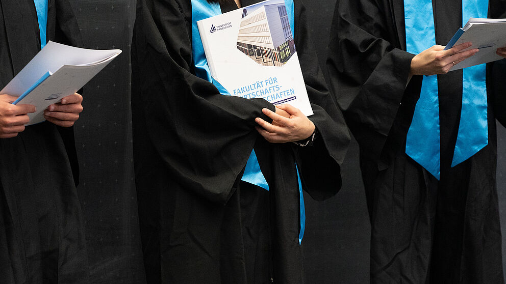 Studierende halten Urkunden in der Hand.