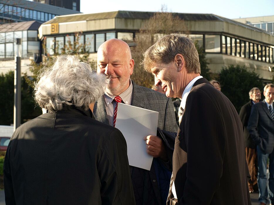 Foto (Bianca Oldekamp): Im Gespräch (von links): Prof. Yuji Takeoka, Künstler und Bildhauer, Heinrich Micus, Leiter der Niederlassung Bielefeld des Bau- und Liegenschaftsbetriebs, und Prof. Dr. Nikolaus Risch unterhalten sich über den „Fakultätengar