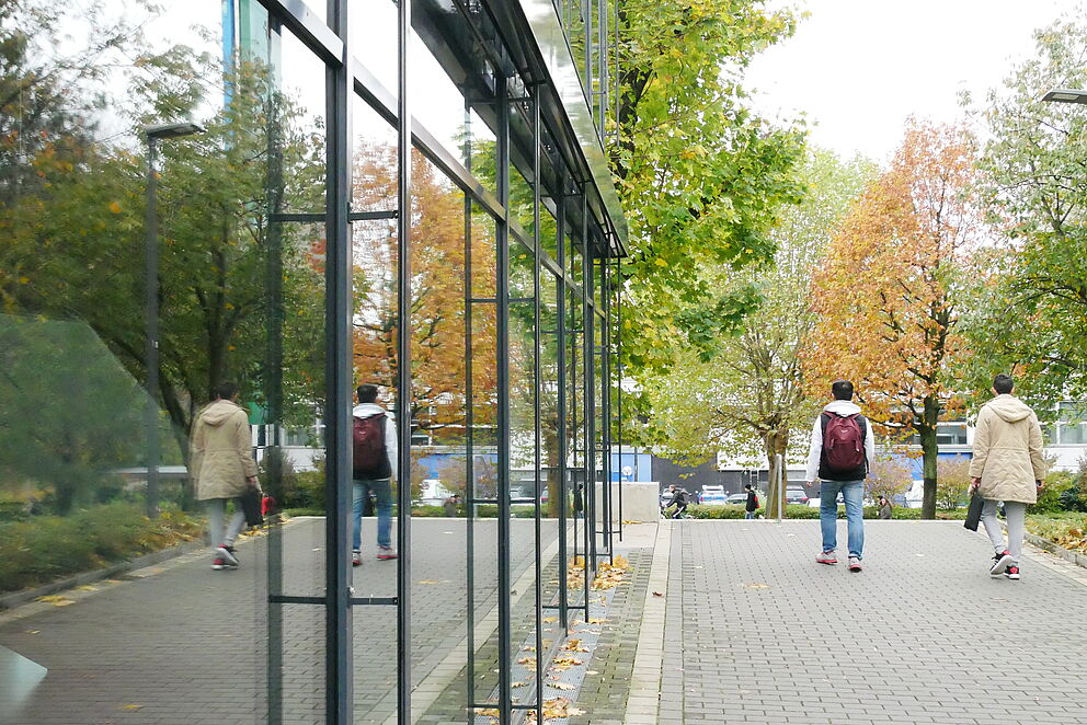 Two people are reflected in the glass front of the mensa at Paderborn University.